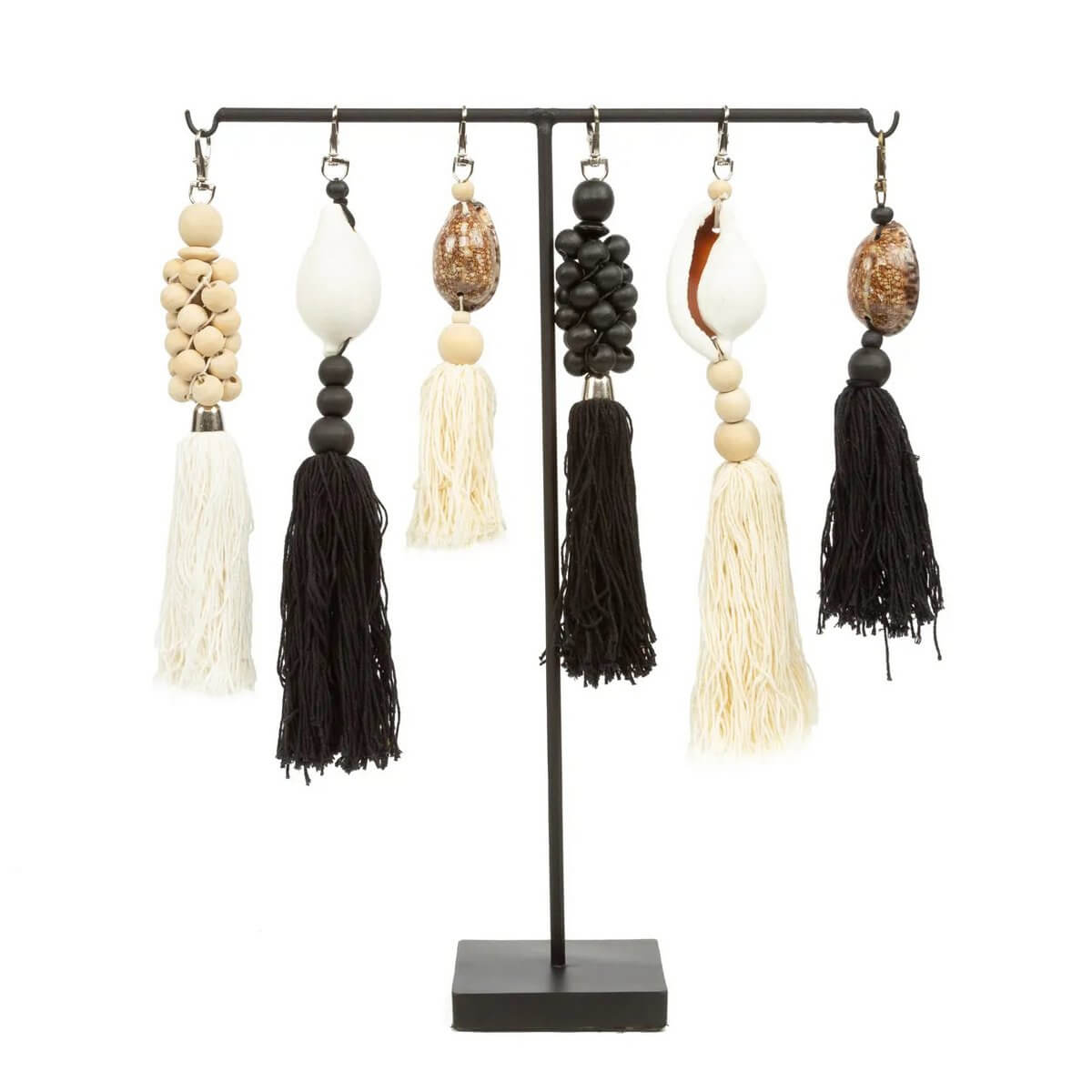 Bohemian houten kralen sleutelhanger in natuurlijk wit met zwarte accenten en kwastjes op een metalen standaard, rustieke stijl.
