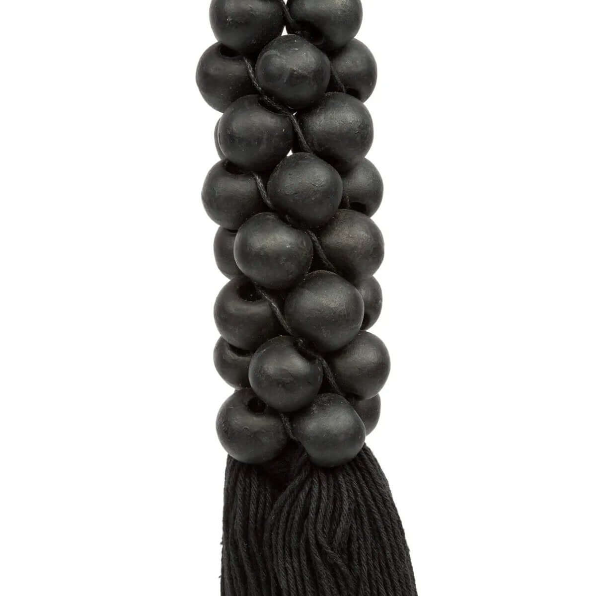 Close-up of black wooden beads with cotton tassel, adding a Bohemian touch to home decor.