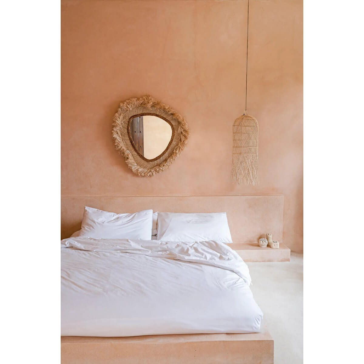 Rustieke slaapkamer met ronde spiegel "De La Contessa" aan de muur, naast modern wit beddengoed.