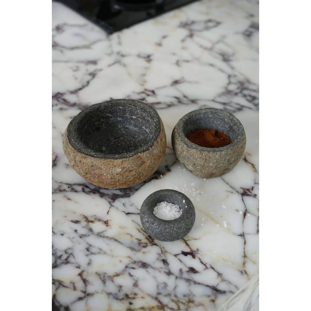 Bohemian handcrafted lavasteen zoutkom set on a marble countertop, showcasing natural textures and versatile kitchen elegance.