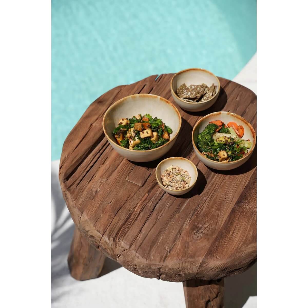 Bohemian De Marabunta rustieke bijzettafel met natuurlijke houtafwerking, versierd met gezonde salades en snacks.