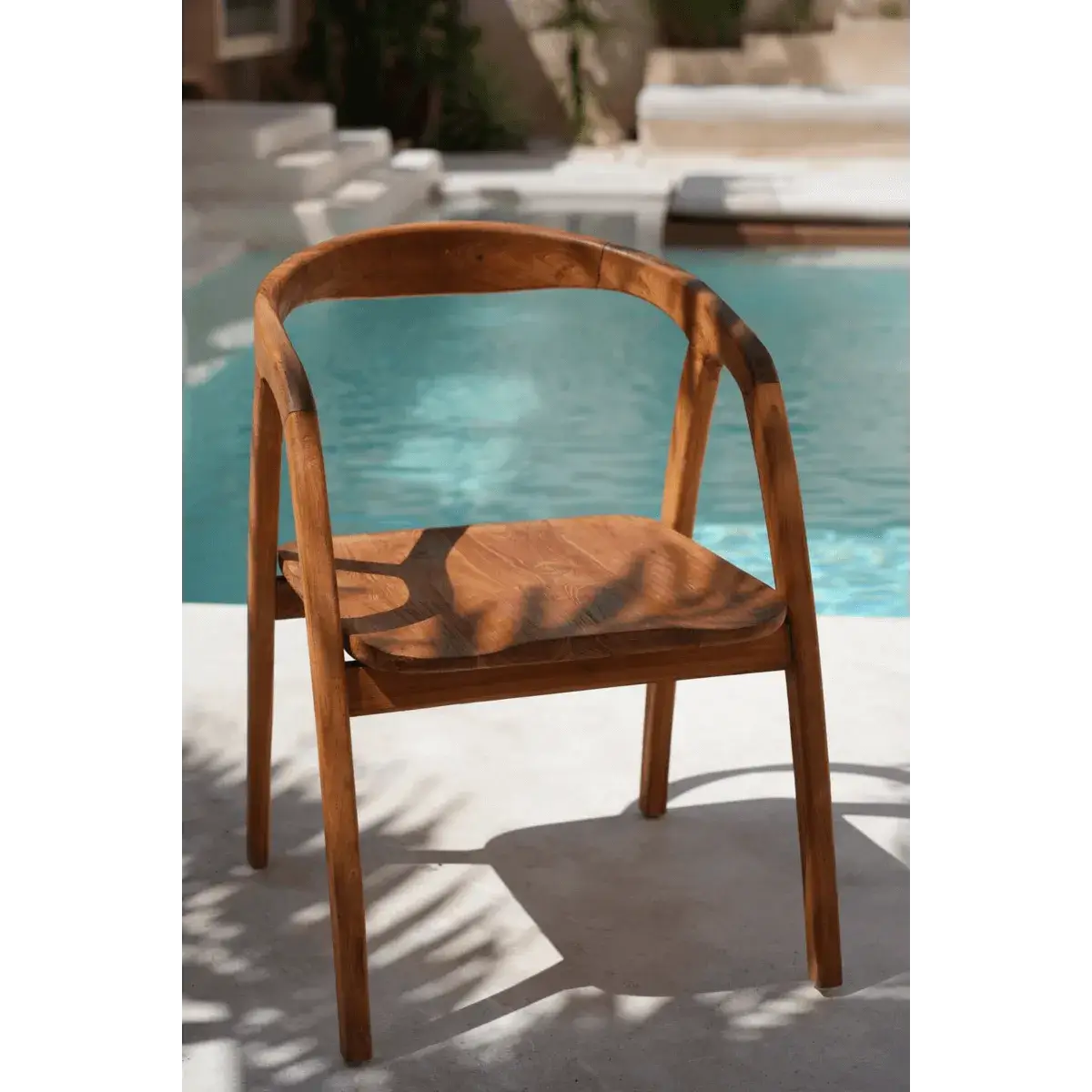 Bohemian De Nihi Watu dining chair by Bazar Bizar Living, positioned near a pool, boasting natural wood aesthetics and elegance.