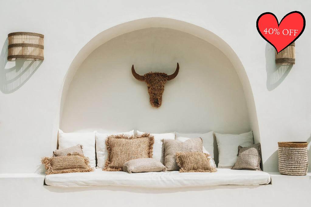 Boho zithoek met beige kussens, zachte katoenen hoezen, en een rustieke stierschedel decoratie, perfect voor een chique inrichting.
