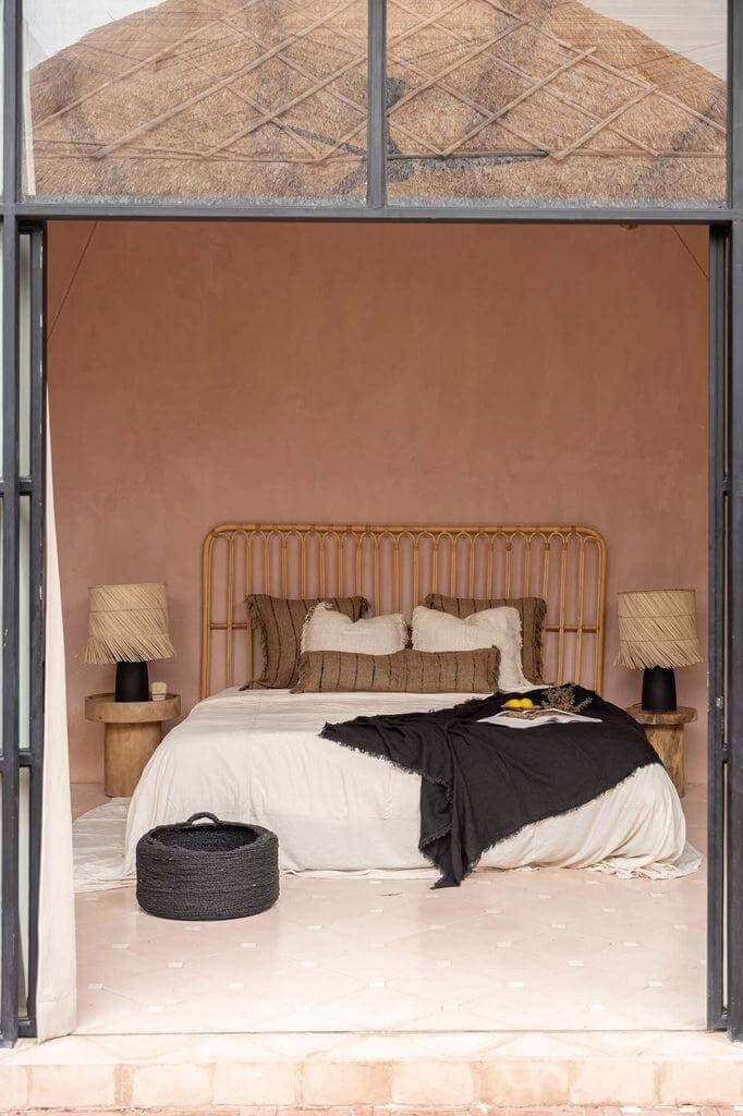 Sfeervolle boho-slaapkamer met rotan hoofdbord, zachte beddengoed en beige-zwart kussen voor een stijlvol interieur.