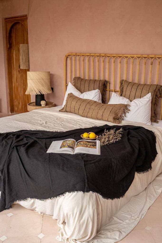 Sfeervolle slaapkamer met De Oh My Gee kussenhoes in beige en zwart op een boho-bed zonder binnenkussen, bohemian stijl.