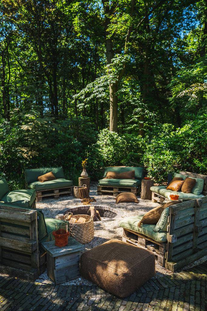 Bohemian buitenruimte met stijlvolle kussens en houten meubels. Perfect voor een chique en comfortabele tuin of patio ervaring.