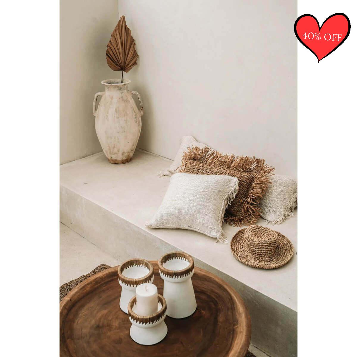 Boho interieur met crème kussenhoes, houten tafel en decoratieve kaarsen. Perfect voor woonkamer of terras.