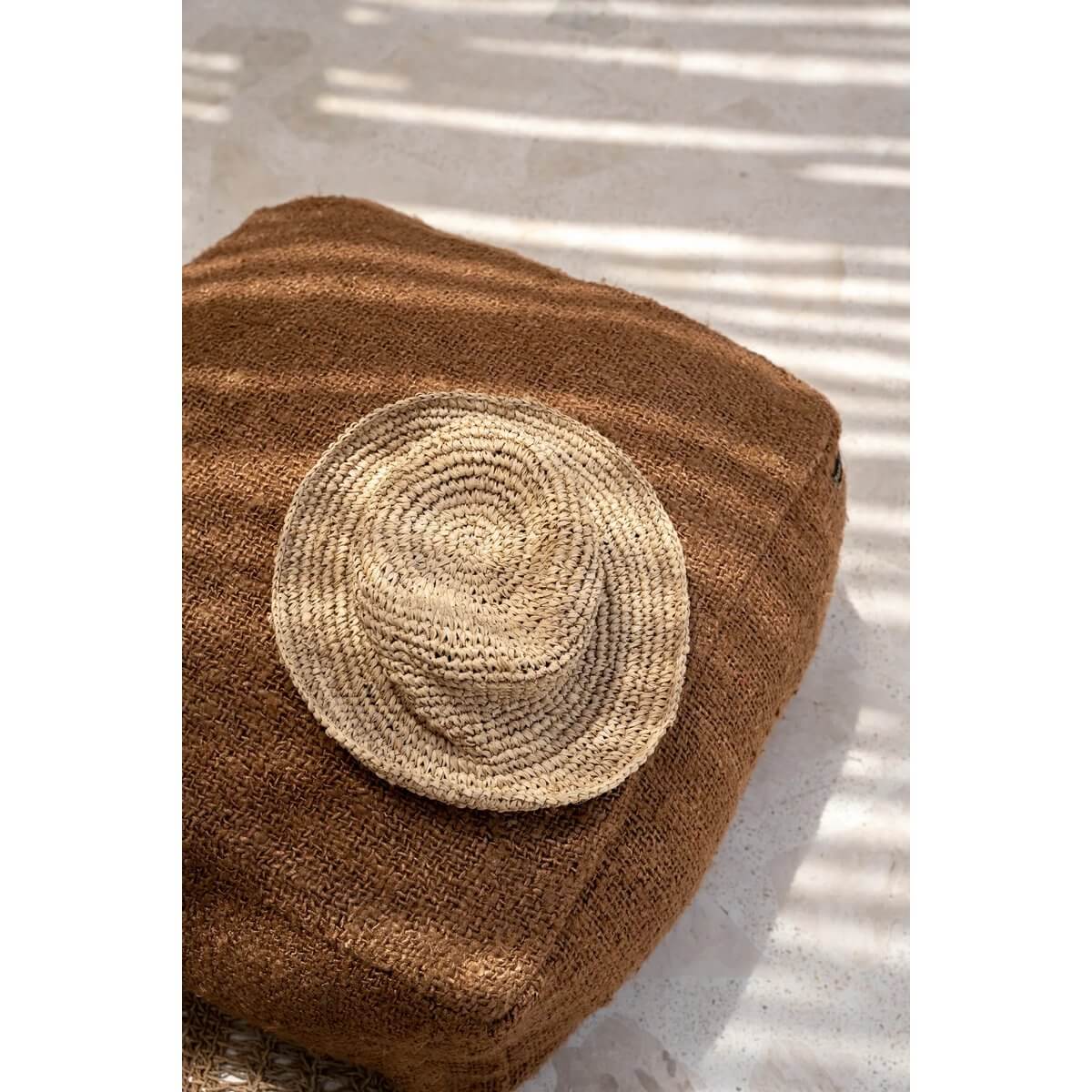 Bohemian style Pantai-hoed made from natural sea grass, resting on a textured brown surface, ideal for chic beach days.