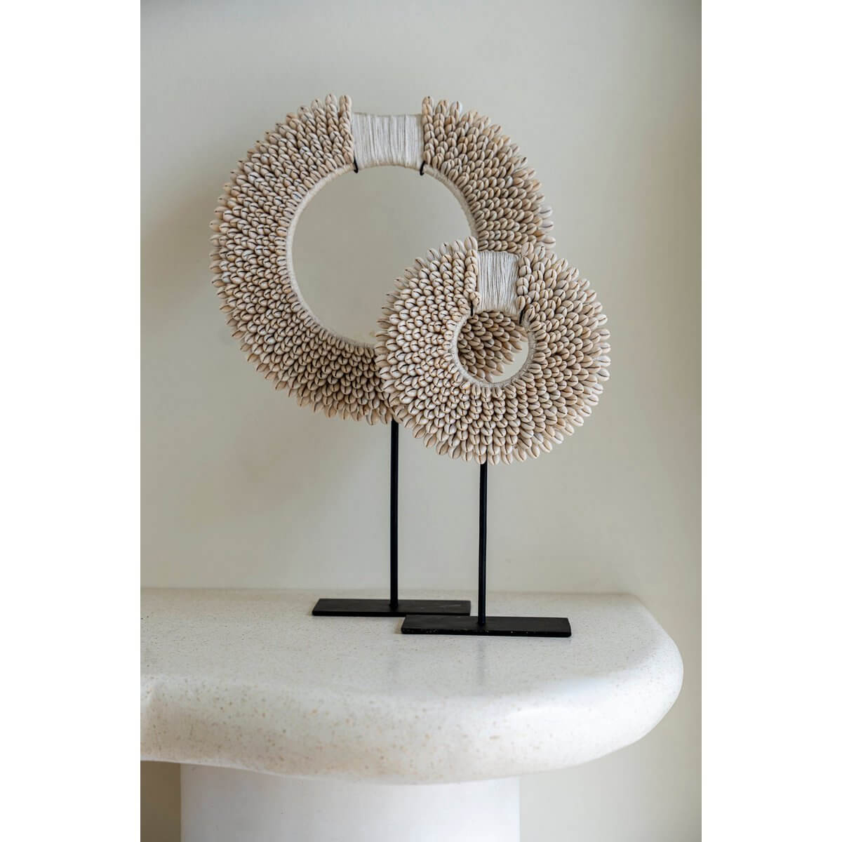 Bohemian flair with white shell disc sculpture on black stand handcrafted by Bazar Bizar Living, adding coastal elegance to decor.