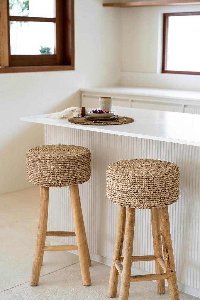 Raffia barkruk in keuken met teakhouten poten en handgeweven zitting, geeft een bohemian en natuurlijke look.