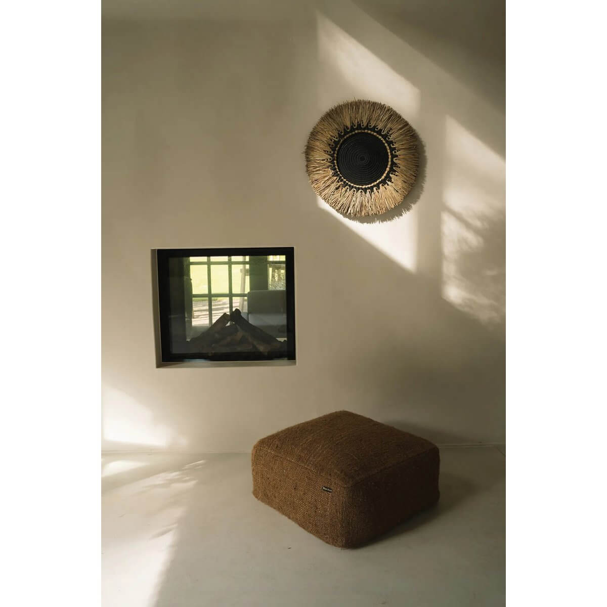 Bohemian wall decor made from black cotton and raffia, adding rustic charm to a minimalist interior with natural light.