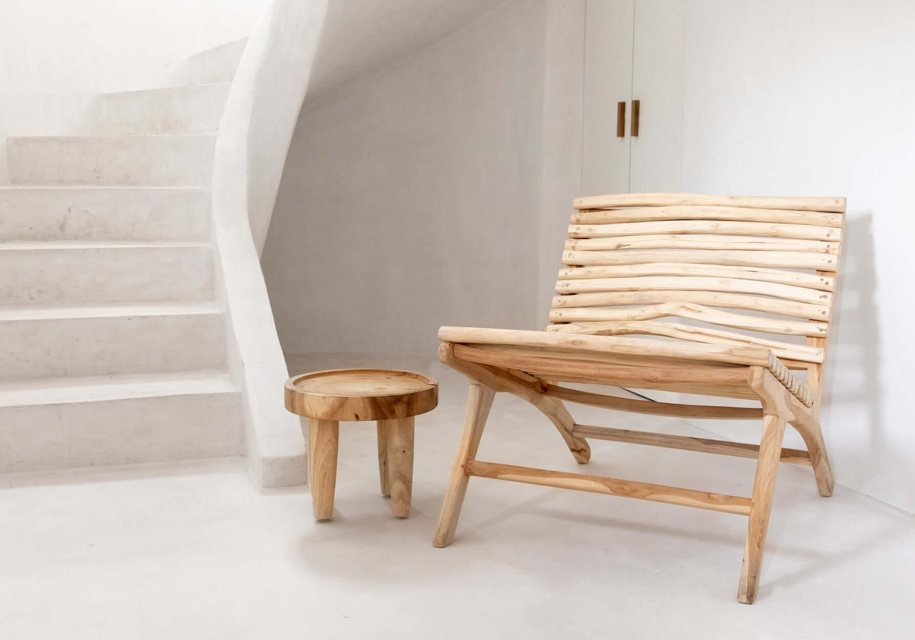 De Samanea bijzettafel naast een houten stoel in een minimalistische kamer, perfect voor binnen of op een boho zomerterras.