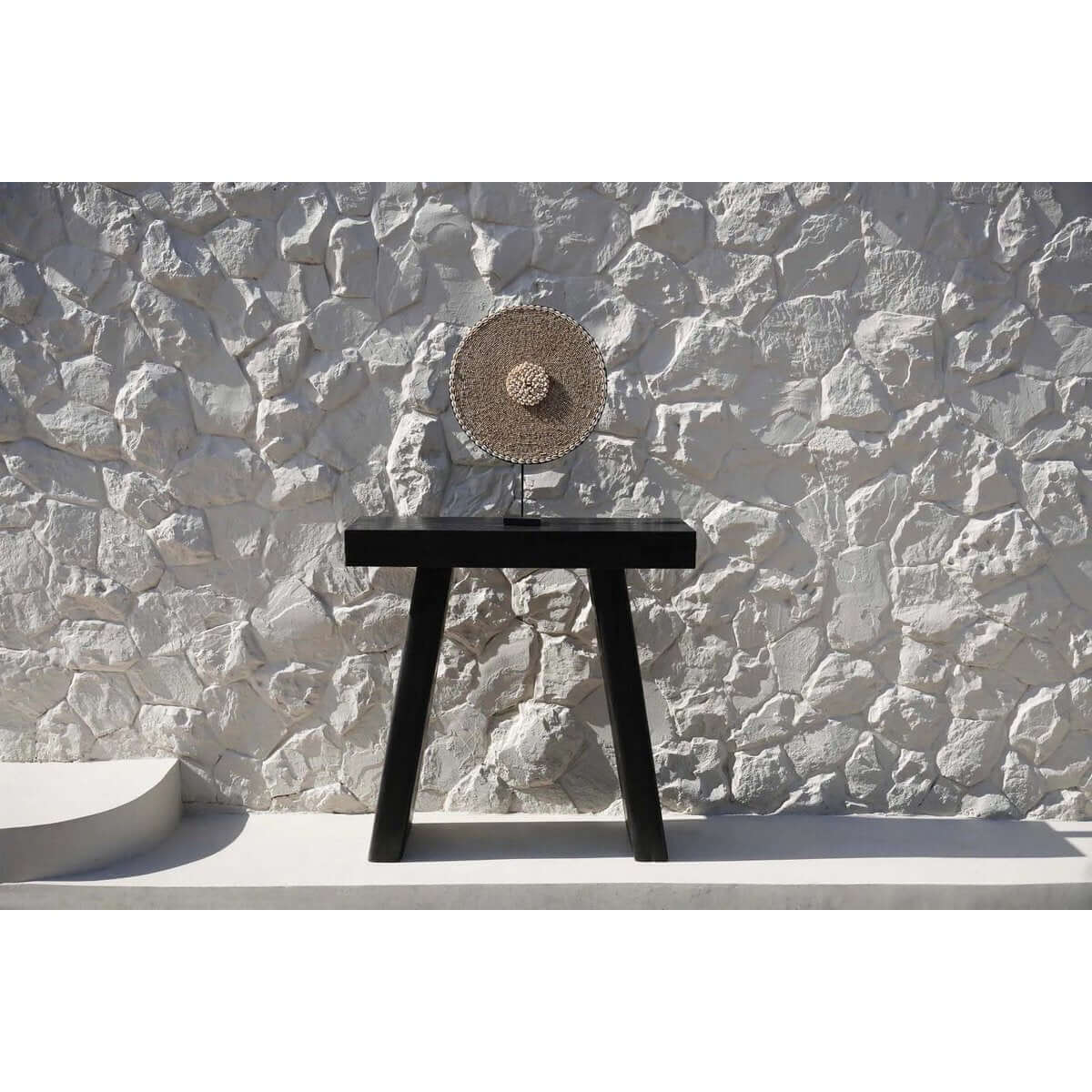 Shell Guadeloupe decor on sleek stand against a textured stone wall, perfect for adding coastal or modern flair to any room.