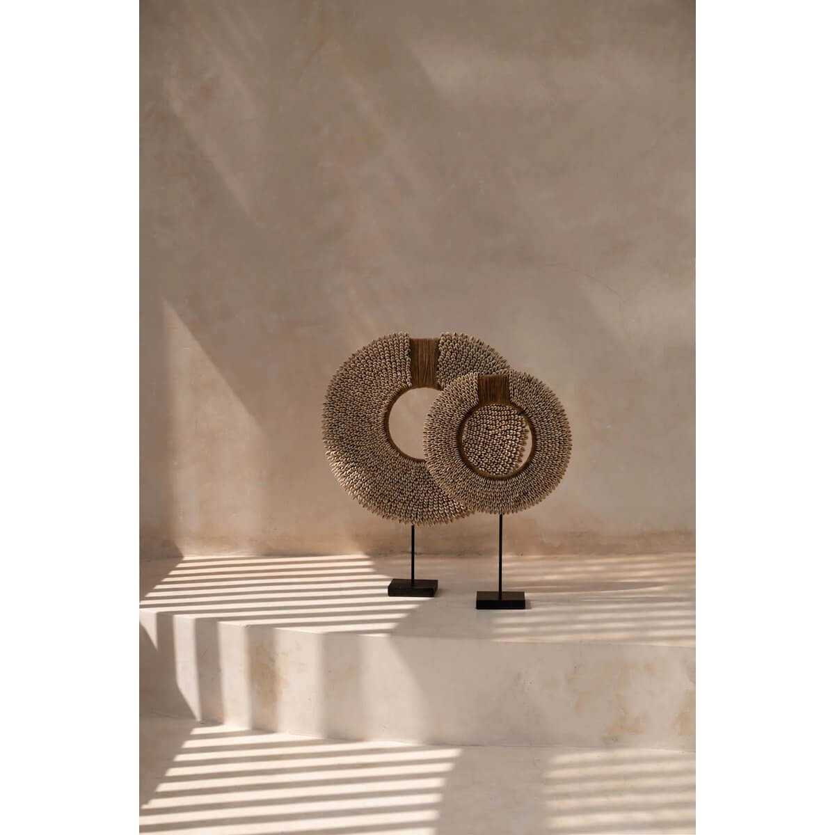 Twee schelpen sculpturen op standaarden, kunstig gearrangeerd als woondecoratie, brengen de oceaan elegant in huis.