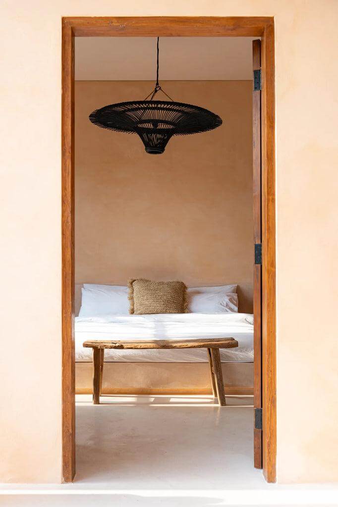Zwarte De Sky Hanglamp XL hangt in een minimalistisch interieur boven een houten tafel en bank. Moderne plafondverlichting in natuurlijke stijl.