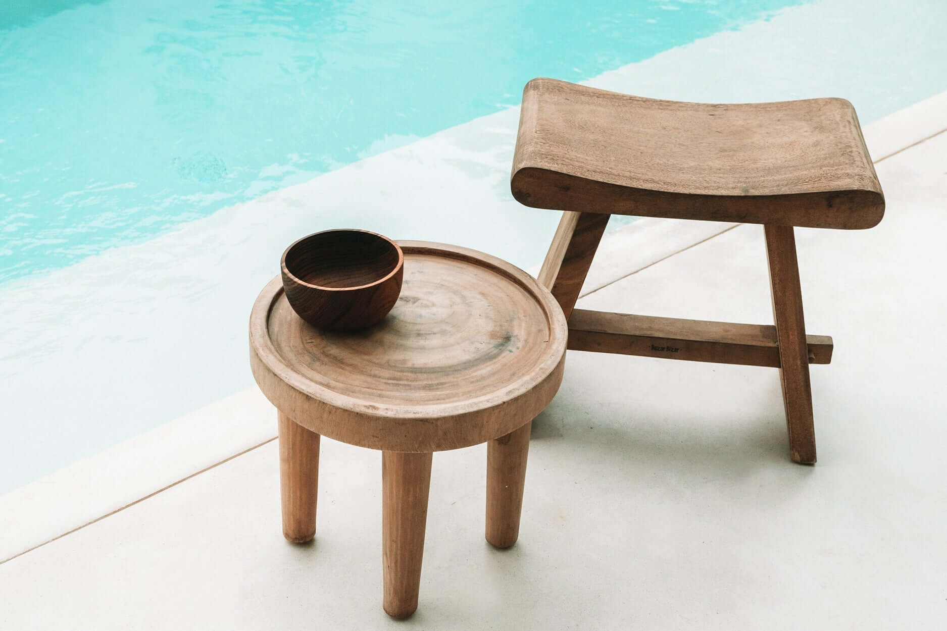 Houten De Suar bijzettafel en stoel bij zwembad, perfect voor zowel binnen als buiten, met tijdloze boho-stijl en natuurlijke charme.