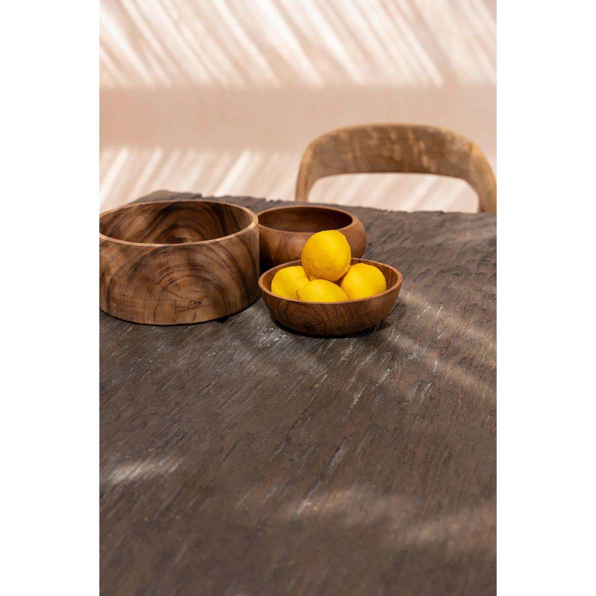 Suar houten slakom met citroenen op een elegante houten tafel.