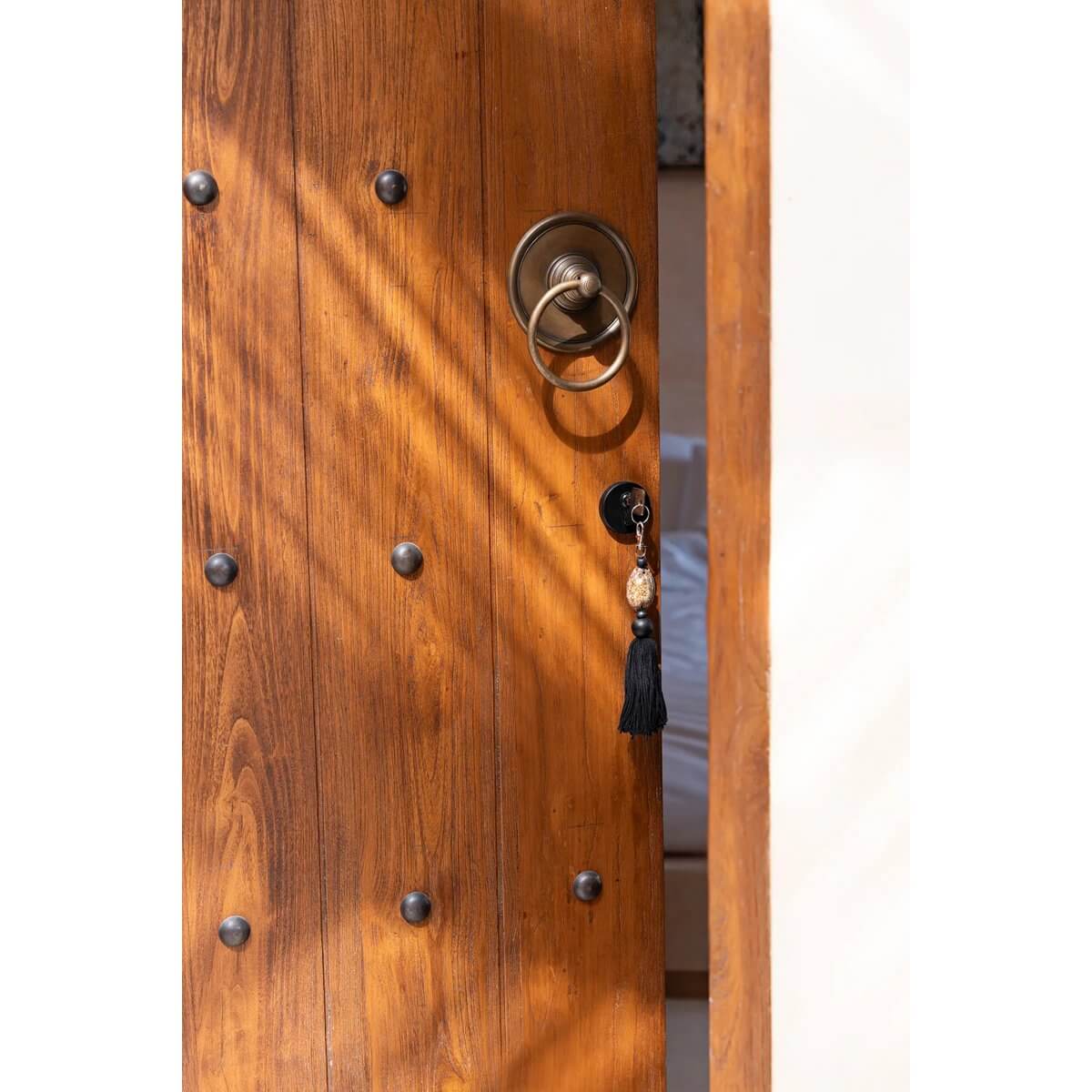 Rustic door with a bohemian Sumbawa keychain in black and brown, adding style and function to your home.