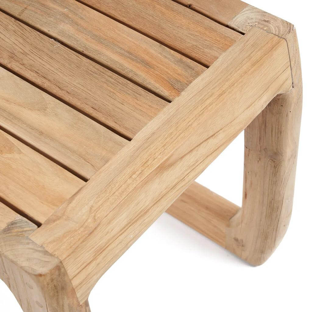 Natuurlijke teakhouten Symi kruk met elegante rondingen en unieke houtpatronen, ideaal als kruk en bijzettafel voor buitengebruik.