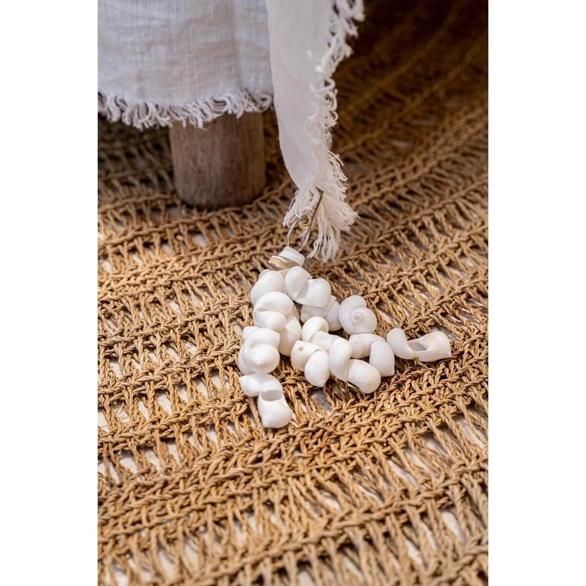 Bohemian tablecloth hanger with white shell design on a woven mat, adding coastal charm to your table decor. Set of 4.