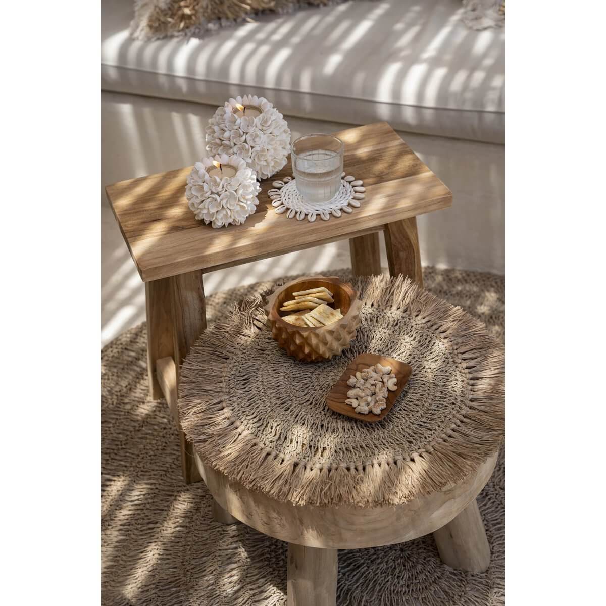 Bohemian-style room with a wooden table and chairs featuring a De Teakwortel Durian Kom filled with snacks, creating a cozy ambiance.