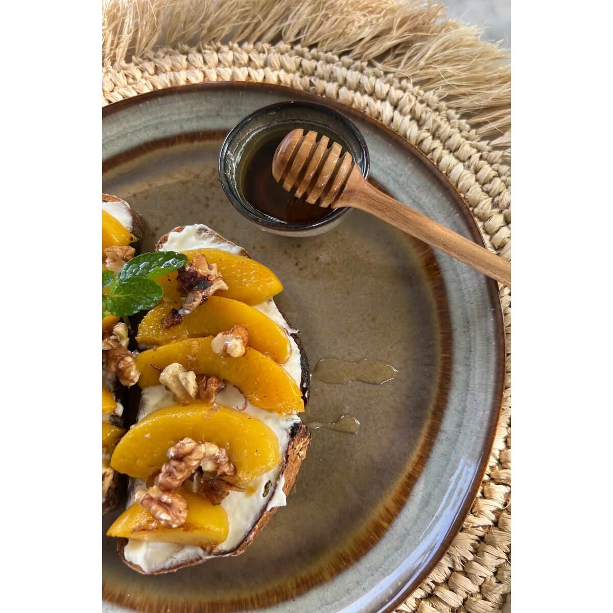 Bohemian-style Teak Root Honey Roller beside a delightful plate of toast with peaches and nuts, serving elegance and taste.