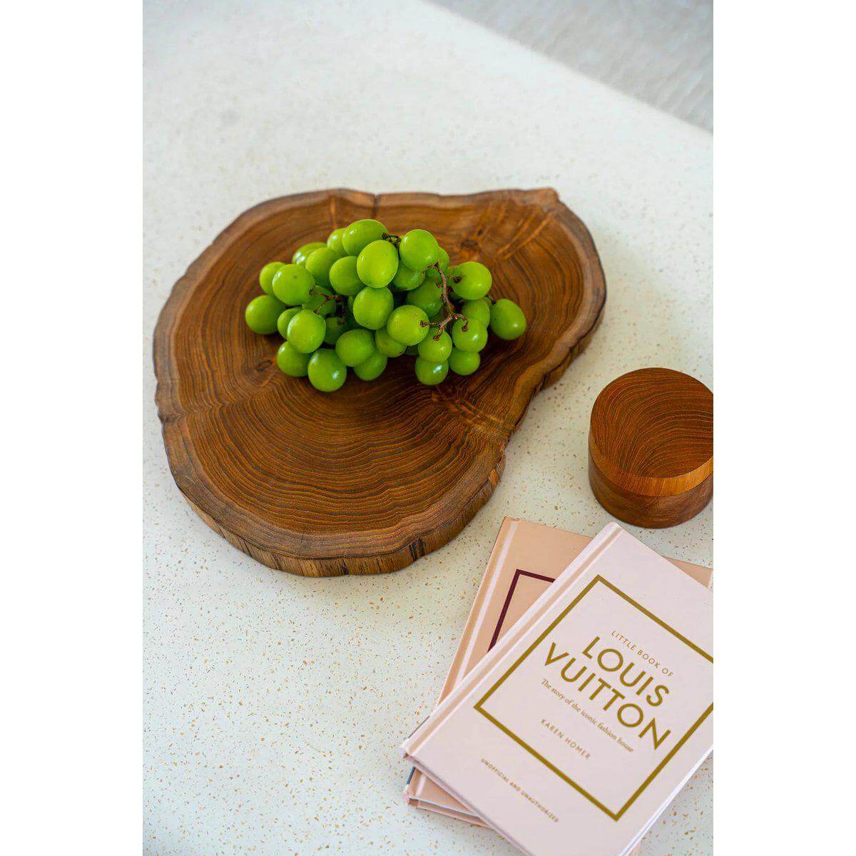 Teakhouten snijplank met groene druiven en boeken op een tafel, handgemaakt in Bali.