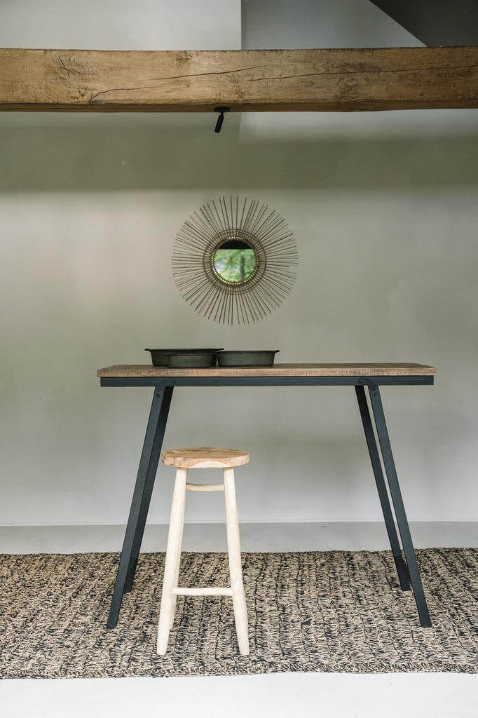 Tropische spiegel in rotan aan de muur boven een moderne tafel en kruk, past perfect bij interieurinrichting van jaren 70-stijl.
