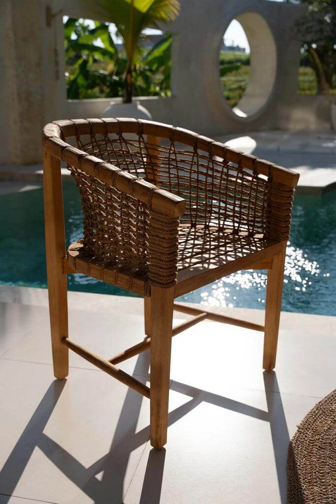 Tugu eetkamerstoel van teakhout en touw bij zwembad, serene elegantie voor buitengebruik, perfect voor tuinfeestjes of relaxen.