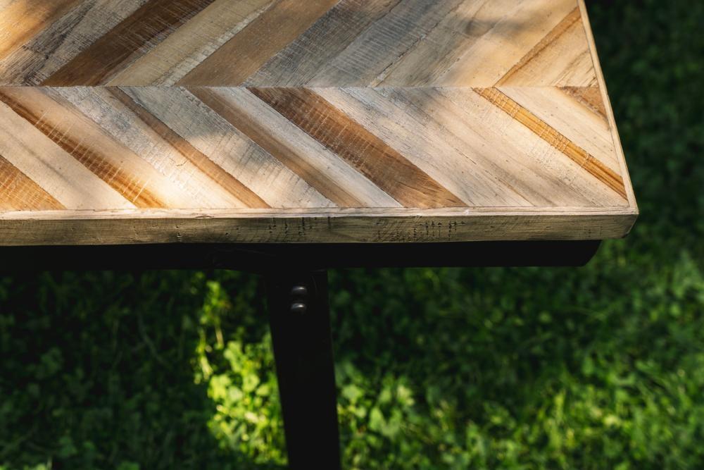 Detail van de Visgraat Bank in natuurlijk teakhout en zwart ijzer, perfect voor binnen- en buitengebruik. Elegante uitstraling met opvouwbaar design.