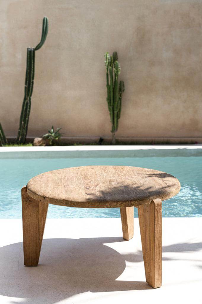 Driepotige Wabi Sabi salontafel van teakhout bij een zwembad, natuurlijke uitstraling, ideaal voor elk interieur.