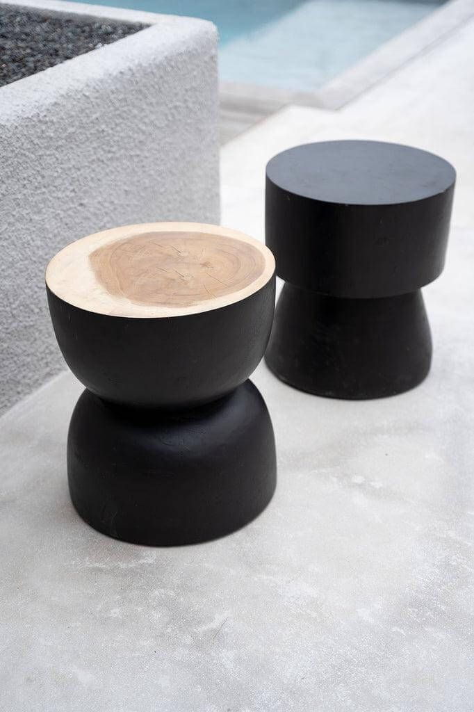 Zwarte Warmi kruk van suarhout als design bijzettafel in modern interieur, opvallende uitstraling en veelzijdig gebruik.