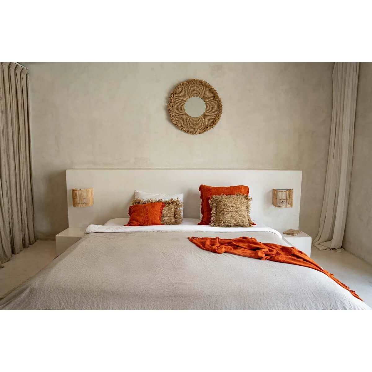 Stijlvolle slaapkamer met De Yema spiegel boven het bed en oranje decoratieve kussens, creëert een rustige en gezellige ambiance.