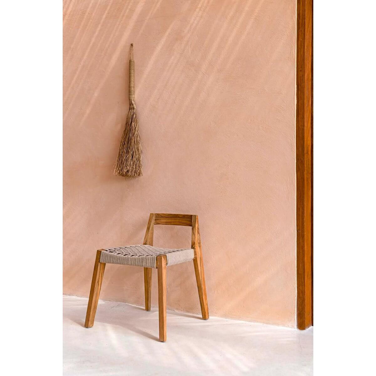 Bohemian wall decor featuring The Grumpy Broom adds character and humor to a sunlit minimalist room with wooden accents.