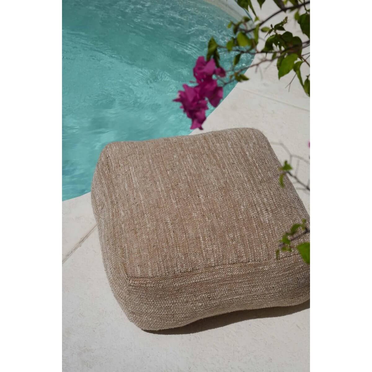Beige comfortabele poef bij zwembad, perfect om te loungen in stijl. Zachte en duurzame stof voor ultiem comfort.