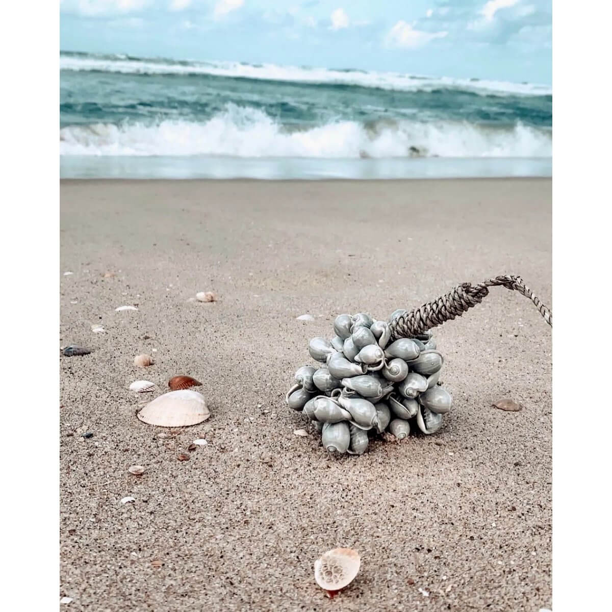 Bohemian grey shell tassel handcrafted on a beach with waves, perfect for home decor by Bazar Bizar Living.