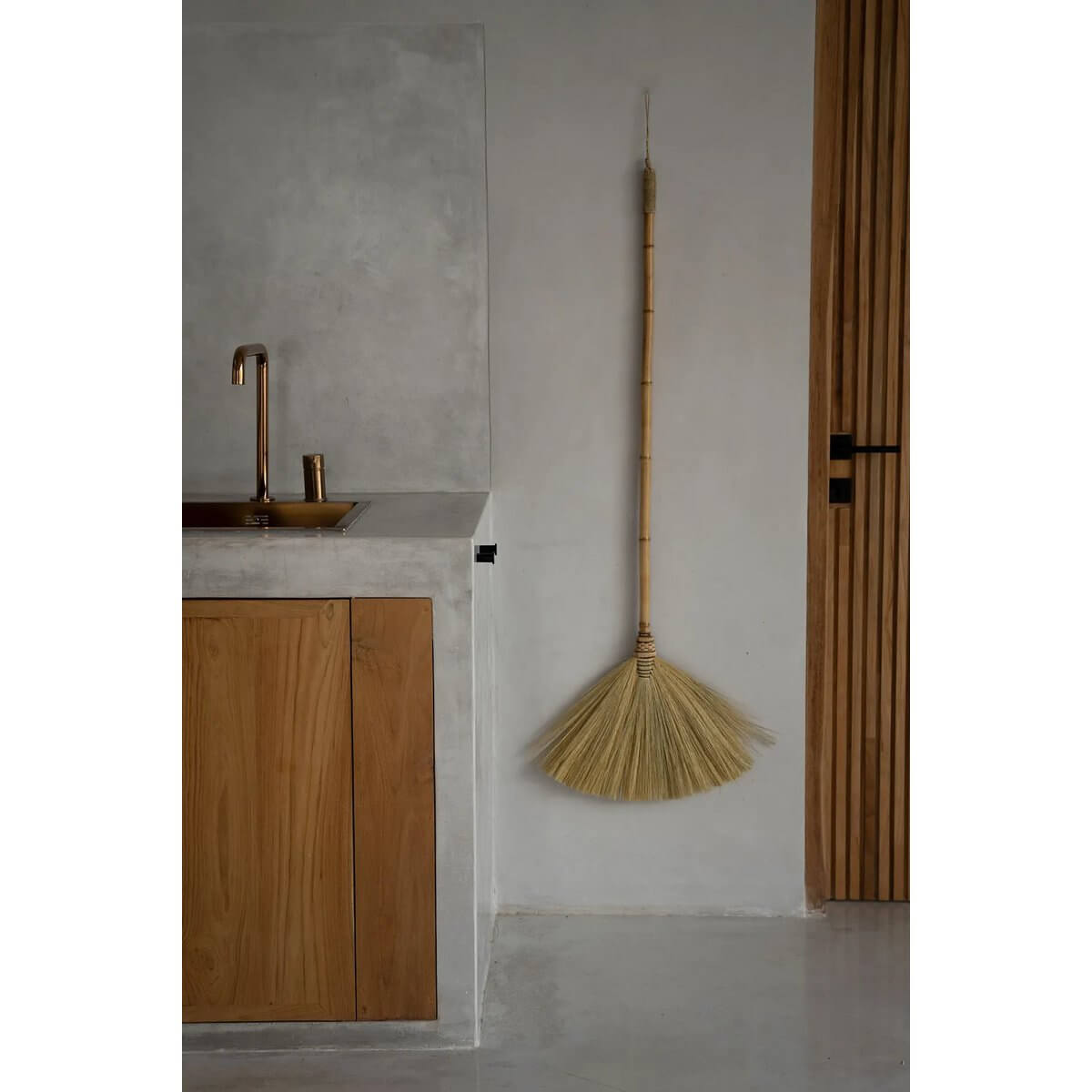 Bohemian style decorative Indonesian broom in a minimalist kitchen space, crafted from multicolored grass, perfect for indoor decor.