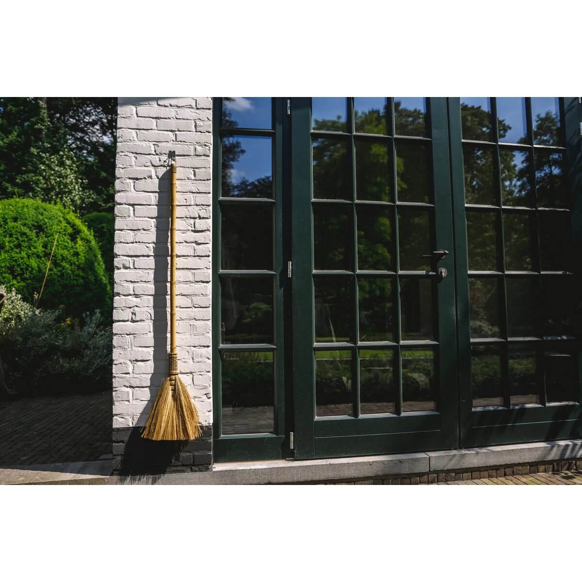 Bohemian Indonesian grass broom as decorative piece in bright sunlit space.