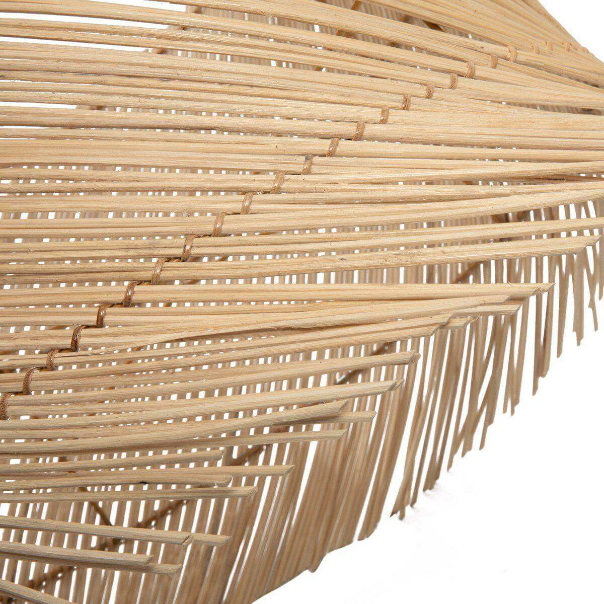 Detail van speelse rotan tafellamp kap met franjes, boho stijl voor sfeerverlichting in woon- of slaapkamer, gemaakt van rotan.