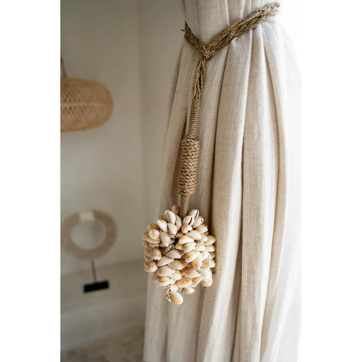 Handmade Balinese shell tassel in soft pink, enhancing bohemian home decor on a curtain. Width: 10cm, Height: 10cm, Length: 50cm.