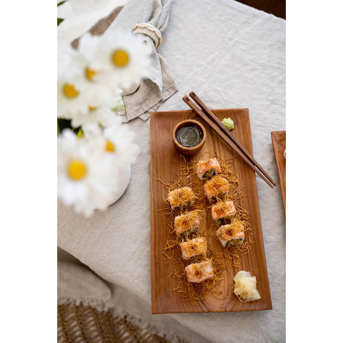Bohemian teak root chopsticks on a wood serving platter with sushi rolls, perfect for sustainable dining and stylish table settings.