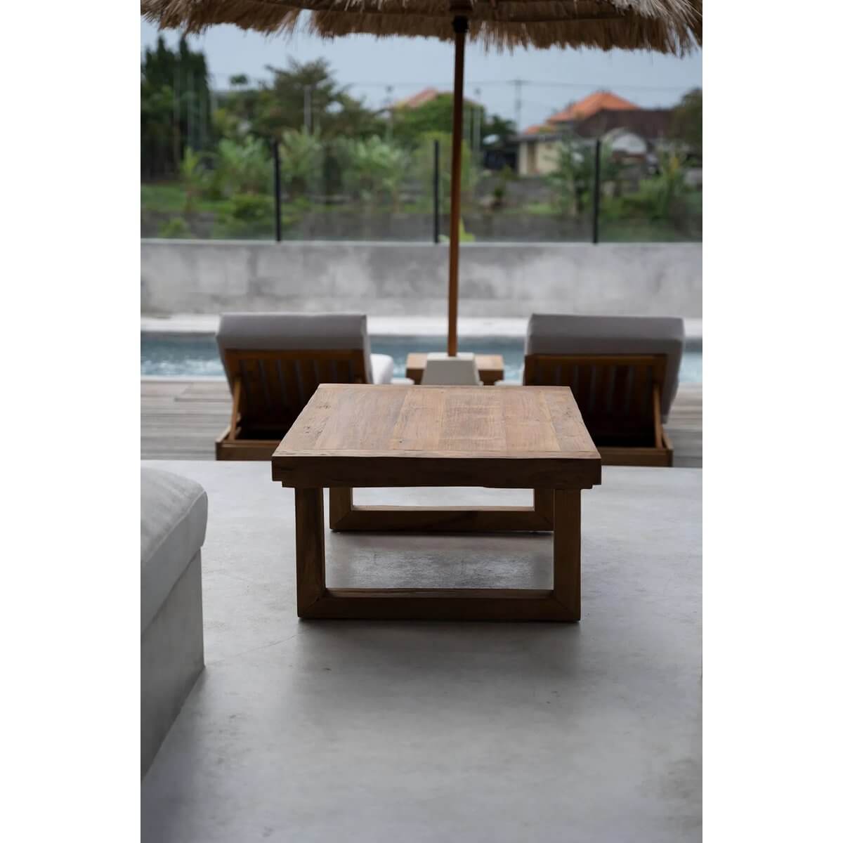 Bohemian reclaimed teak coffee table by poolside with wooden loungers and umbrella, showcasing natural durable beauty.