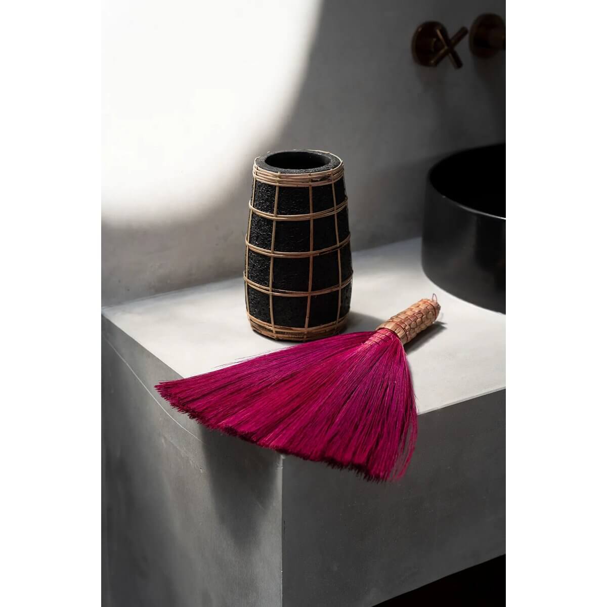 Bohemian pink hand broom made from Indonesian grass on a countertop, adding a chic touch to home decor.
