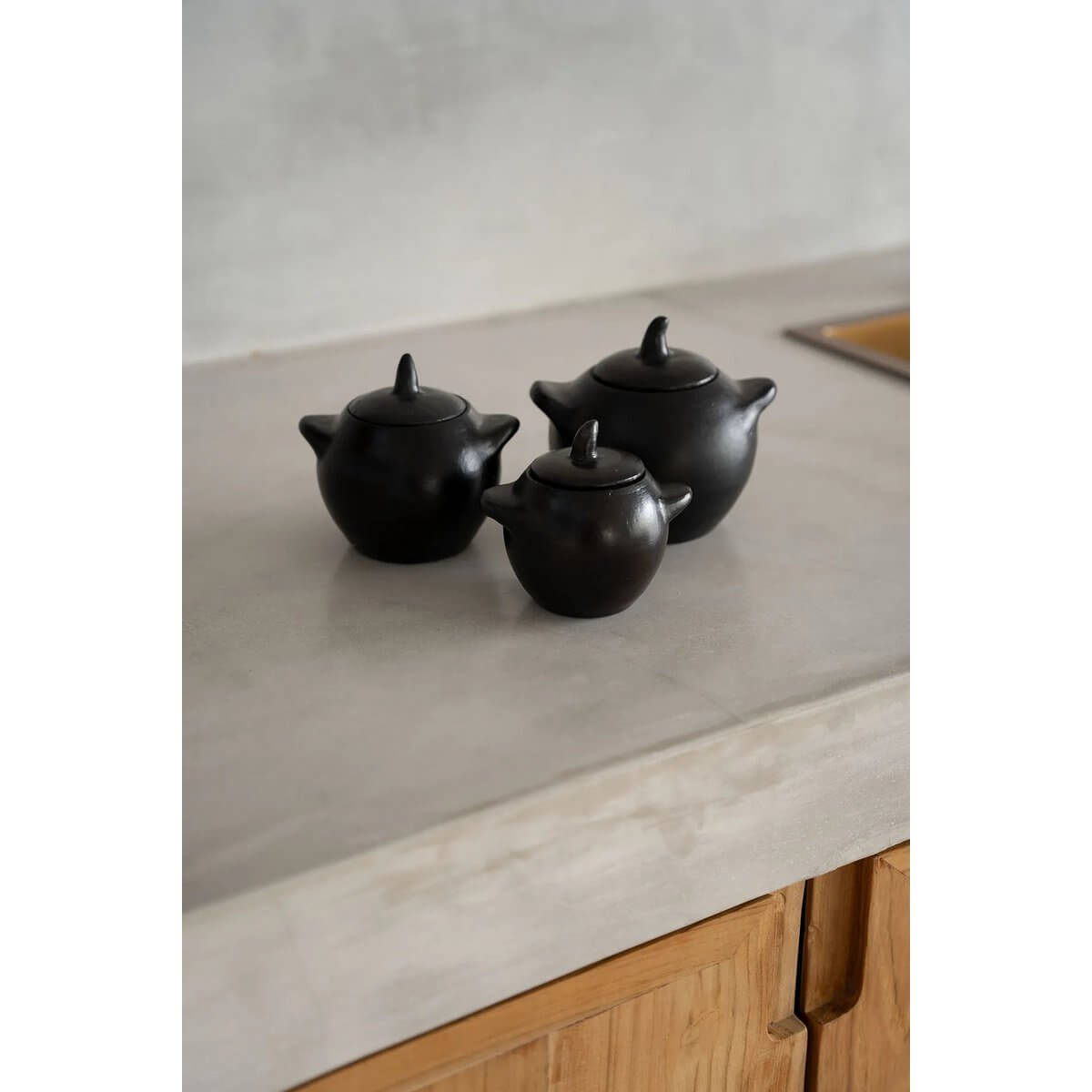 Set of three black-burnt bohemian pots on a kitchen counter, perfect for adding flair to your meals with sugar or sauces.
