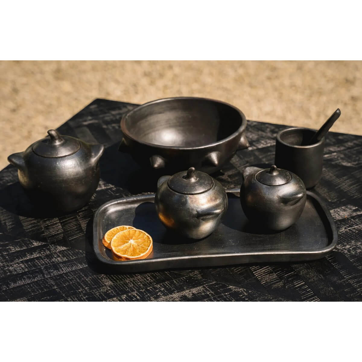 De verbrande pot Bohemian black-burnt pottery set with teapot, bowl, and jars on table, perfect for stylish, Insta-licious dining.