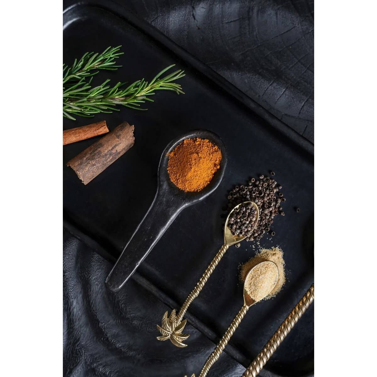 Black tapas spoon from Burned collection with spices, rosemary, and rustic decor; perfect Bohemian touch for stylish dining. 