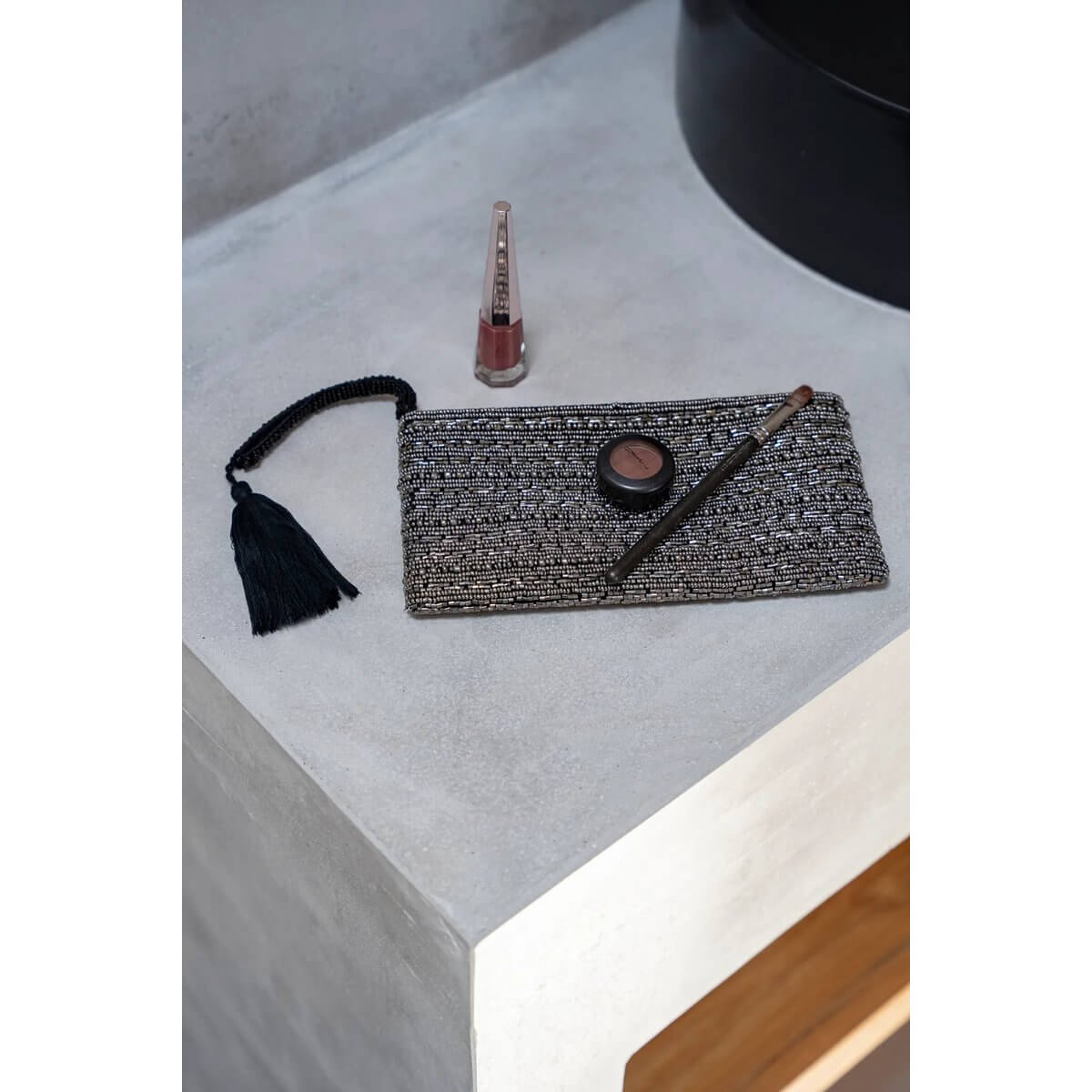 Sleek and stylish Bohemian silver clutch on a table with makeup essentials, ready to add sparkle to your look.