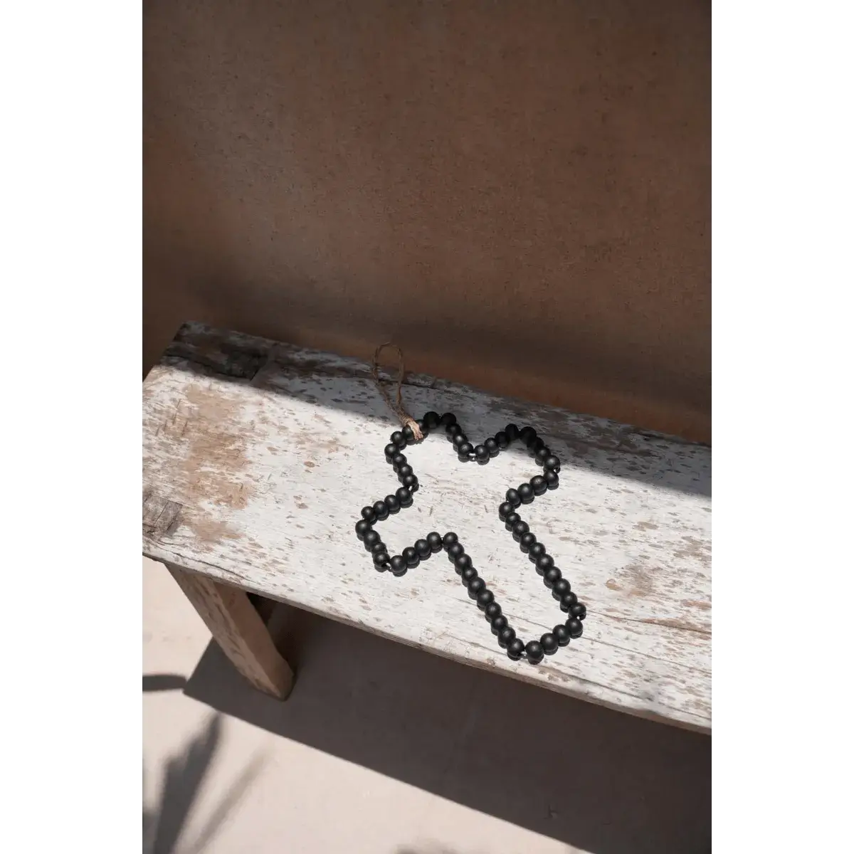 Bohemian black wooden cross with beads on rustic bench, perfect for home decor by Bazar Bizar Living.