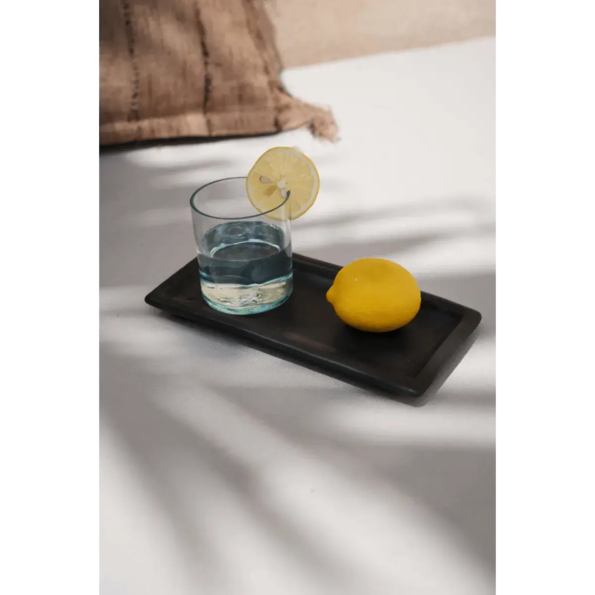 Bohemian glass with lemon slice on tray, eco-friendly and made from recycled materials, blending style with sustainability.