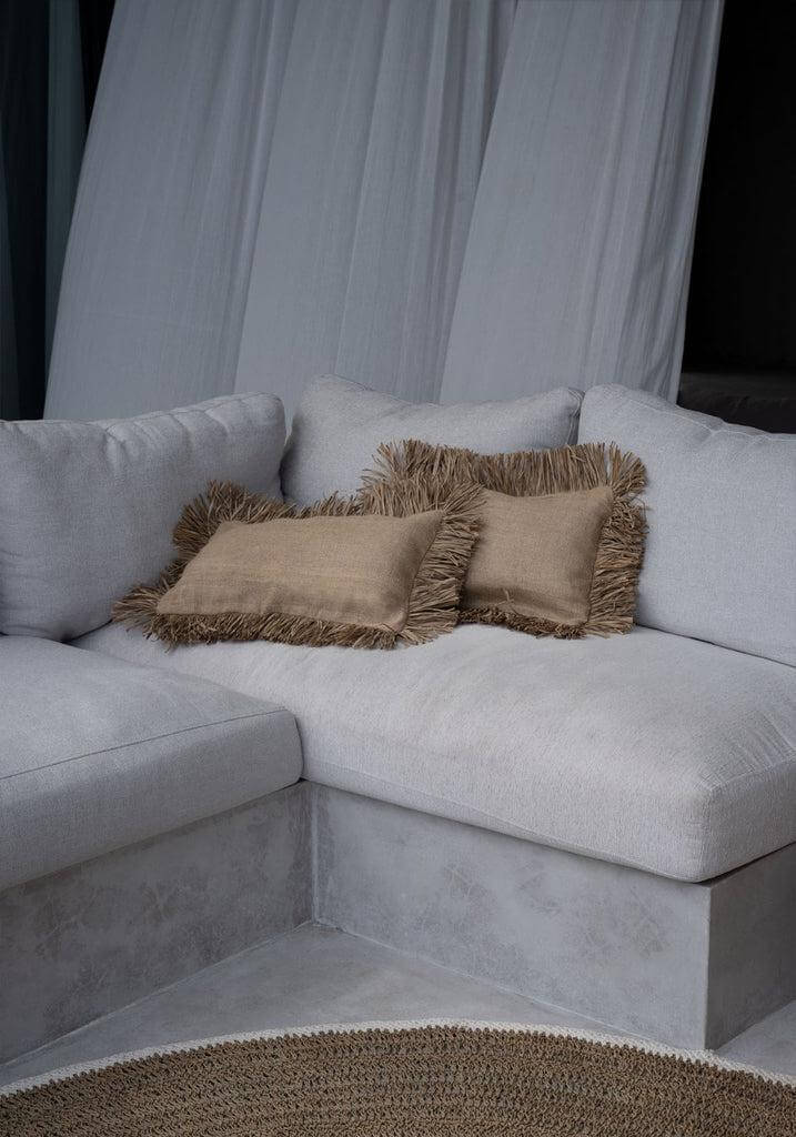 Lichte hoekbank met beige kussens en zeegras vloerkleed voor een gezellige woonkamer sfeer.